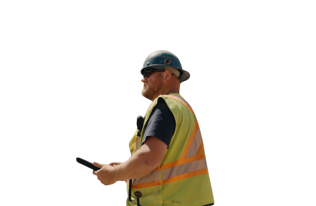 Profile view of a construction worker wearing a hard hat, safety sunglasses, and a high-visibility vest while holding a mobile device.