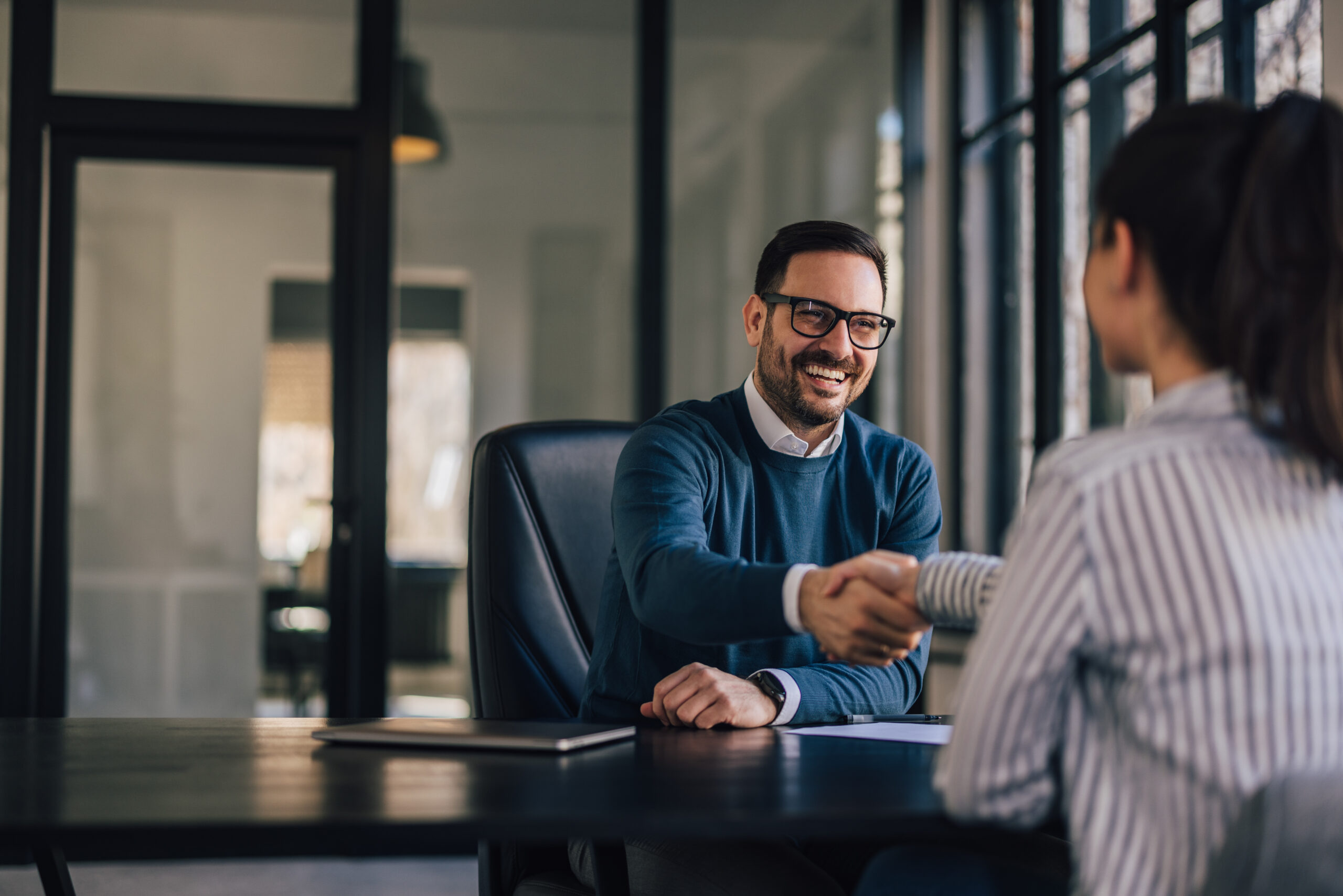Happy businessman, shaking hands with the newly employed person. Man and women shaking hands in business setting conference room